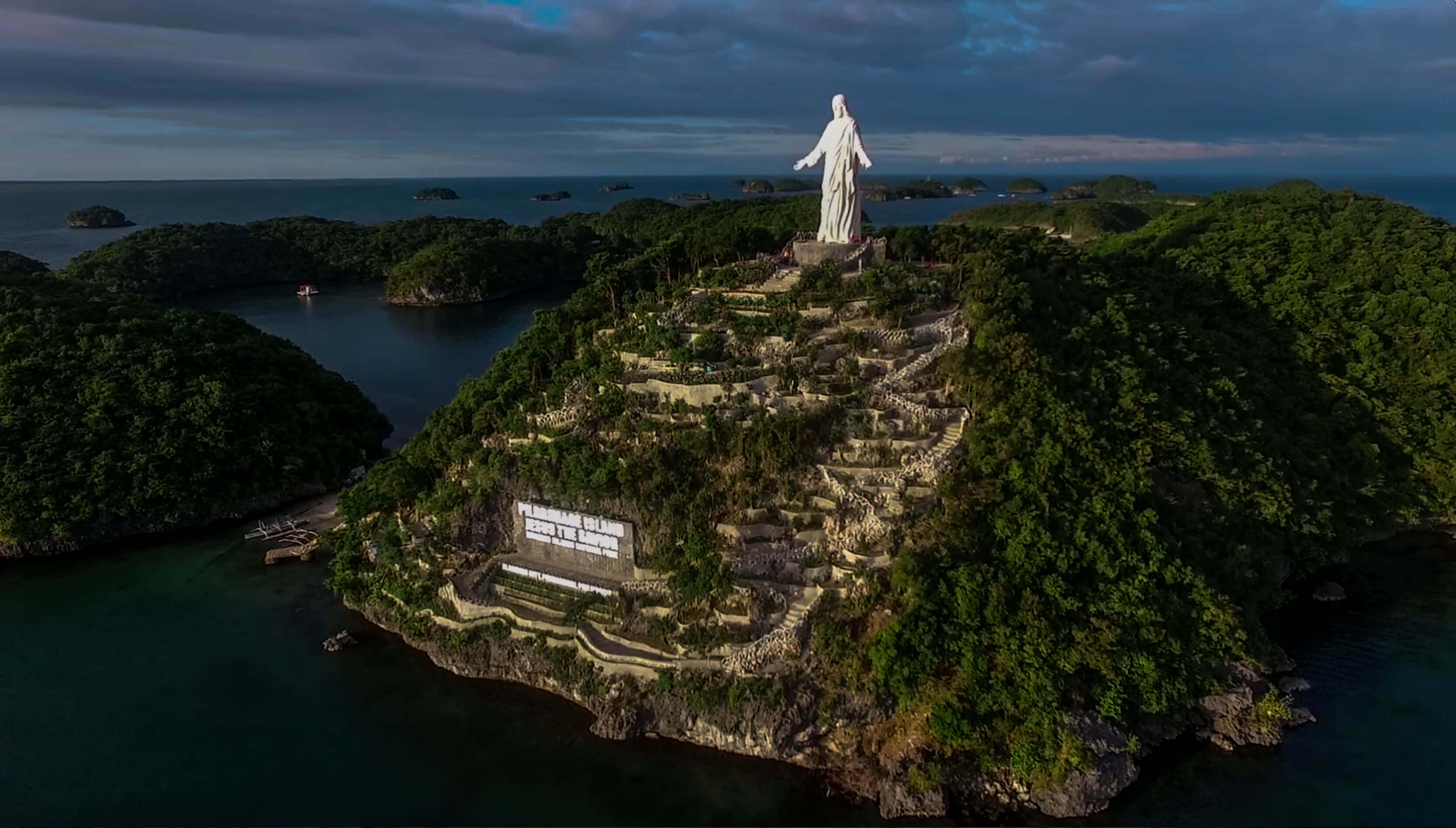 drone shot of pilgrimage island at with jesus statue at hundred islands nature park in philippines